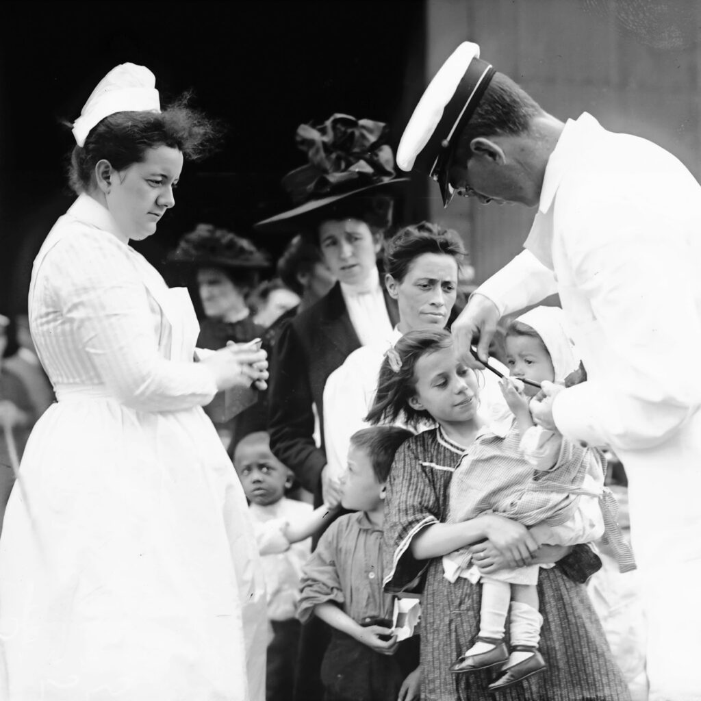 Medical staff check the health of an infant in the line to board, 1910