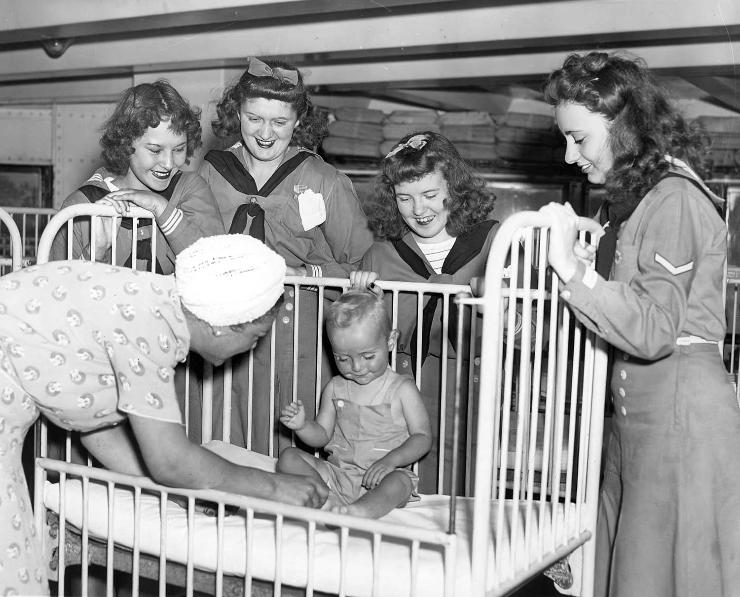 Mariner Girl Scouts surround a crib as a baby gets attention