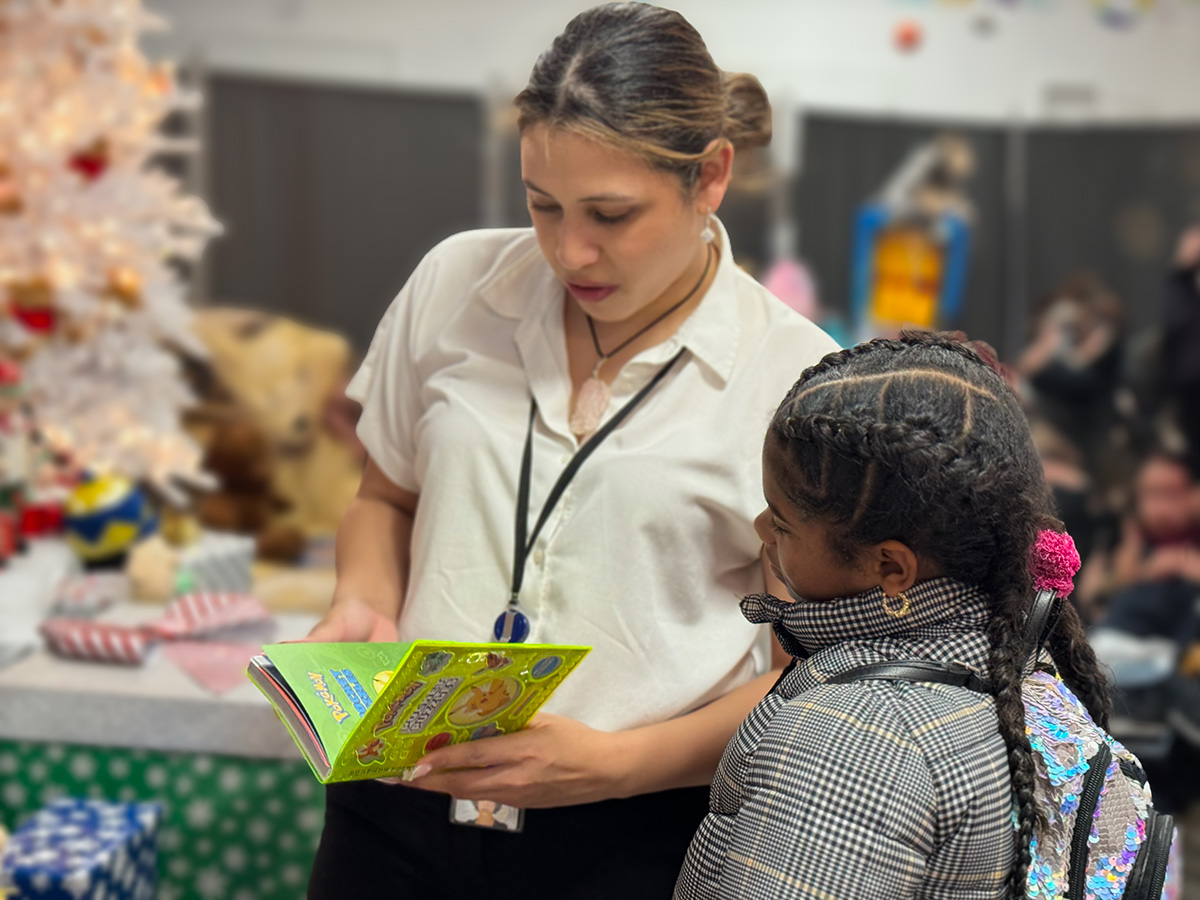 Woman reading to a young girl at Candy Cane Lane