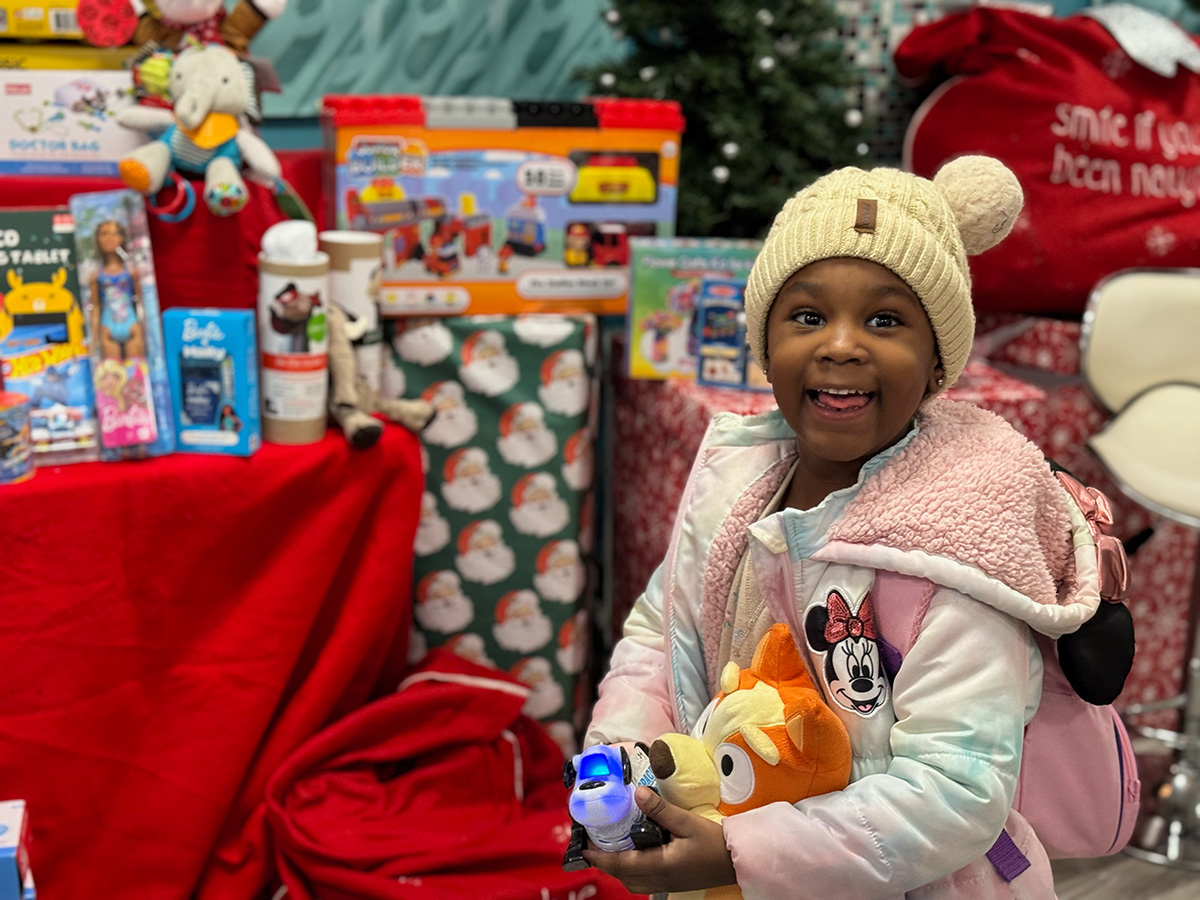 Girl holding toys at Candy Cane Lane 2023